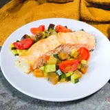 Filetto di salmone su un letto di verdure miste, un'ottima idea su cosa abbinare al salmone per un pasto leggero e saporito.