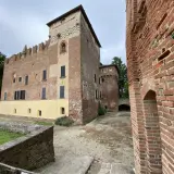 Antico castello in mattoni rossi, un gioiello da scoprire nella Lomellina, con torri merlate e un cortile interno.