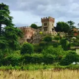 La rocca di Montalfeo, un castello medievale circondato da alberi secolari e vegetazione lussureggiante, domina la collina.
