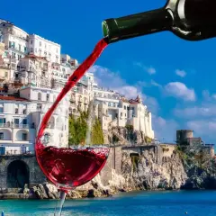 Un bicchiere di vino rosso si riempie con vista sulla costa amalfitana, un assaggio dei vini Campania.