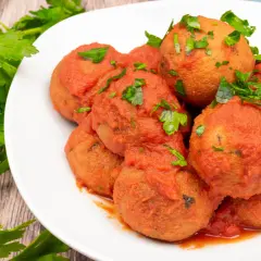 Pallotte cacio e ova, gustose polpette in salsa di pomodoro, guarnite con prezzemolo fresco.