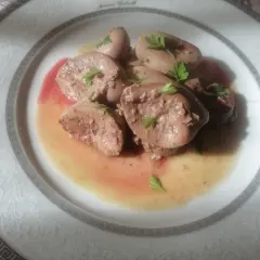 Piatto di rognone trifolato, guarnito con prezzemolo fresco, servito su un elegante piatto bianco con decorazioni in rilievo.