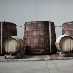Grandi botti di legno con cerchi rossi, una piccola botte in primo piano con la scritta "Cru" che evoca il significato di origine e qualità.
