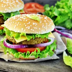 Hamburger vegetali ricetta: due succulenti hamburger con panino ai semi di sesamo, insalata croccante, pomodoro, cipolla rossa e formaggio.