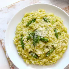 Risotto cremoso con asparagi freschi e robiola, guarnito con parmigiano grattugiato. Un piatto primaverile delizioso.