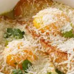 Piatto tipico Pavia: tortelli di zucca dorati, ripieni di formaggio e guarniti con erbe fresche e abbondante parmigiano grattugiato.
