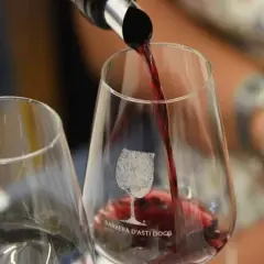 Versando il vino rosso in un bicchiere con inciso "Barbera d'Asti DOCG". Un'esperienza per gustare la barbera migliore.