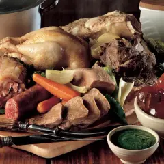 Un ricco bollito con mostarda, composto da pollo, lingua, salumi e verdure, pronto per essere gustato.