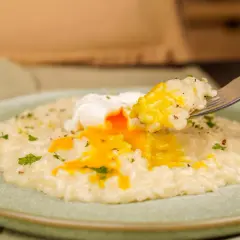 Un cremoso risotto con un uovo in camicia, il cui tuorlo dorato si riversa sul riso. Un piatto invitante e gustoso.