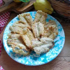 A plate of golden fried anchovies with a light, crispy coating, seasoned with pepper.