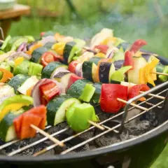 Spiedini colorati di verdure fresche, pronti per una deliziosa grigliata vegetariana. Zucchine, peperoni, melanzane e cipolle cuociono sulla brace.