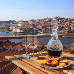 Un bicchiere di vino porto e dolci su un tavolo con vista sulla città di Porto, Portogallo.