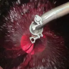 Il rimontaggio del vino in vasca, con il mosto rosso che vortica attorno a un ugello metallico.