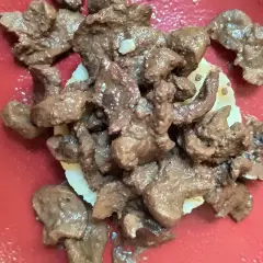 Un succulento piatto di frittura di maiale, servito su una base di patate, su un piatto rosso.