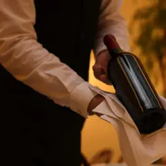 Cameriere serve un vino costoso, con eleganza, su un tovagliolo bianco.