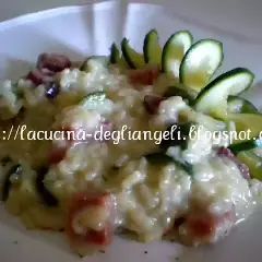 Risotto cremoso con robiola e speck croccante, guarnito con zucchine fresche. Un piatto delizioso e invitante.