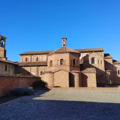 Lomello cosa vedere: la Basilica di San Magno, un gioiello romanico in mattoni rossi, con il suo campanile svettante sotto un cielo azzurro.