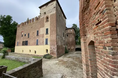 Antico castello in mattoni rossi, un gioiello da scoprire nella Lomellina, con torri merlate e un cortile interno.