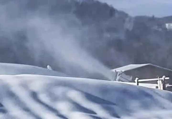 Neve artificiale sul Monte Penice, con un cannone spara-neve in azione e un rifugio sullo sfondo.