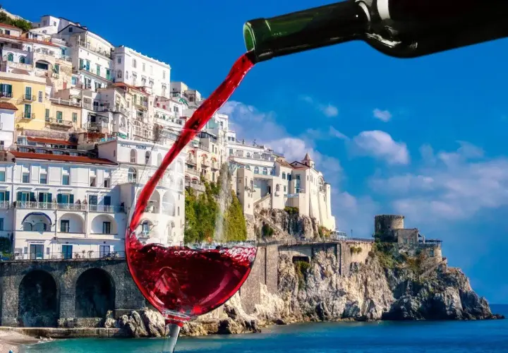 Un bicchiere di vino rosso si riempie con vista sulla costa amalfitana, un assaggio dei vini Campania.