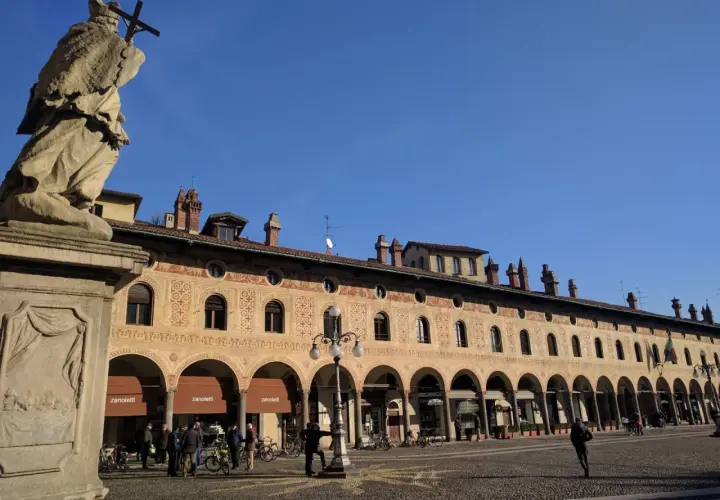 Statua e portici decorati in Piazza Ducale, un luogo imperdibile tra le cose da vedere a Vigevano.