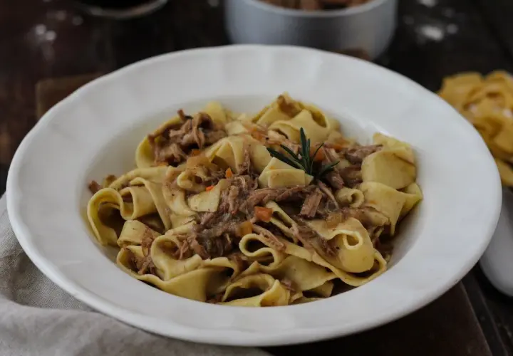 Pappardelle con ragù di carne, un classico dei primi piatti di carne, guarnite con rosmarino.