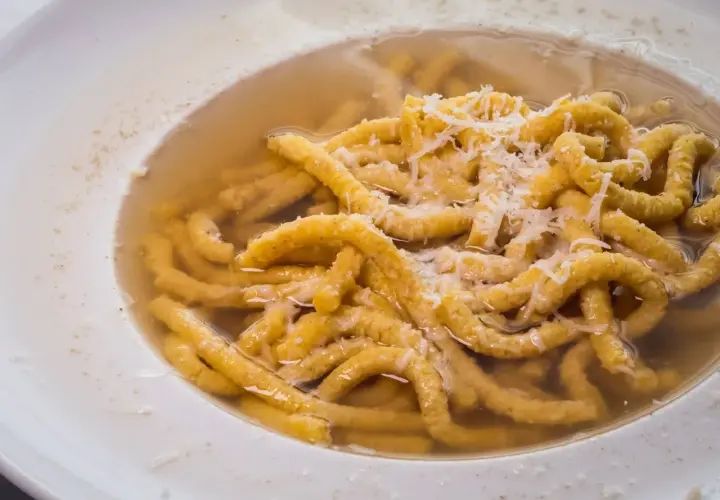Passatelli in brodo, un classico dei cibi tipici dell'Emilia Romagna, con abbondante parmigiano grattugiato.