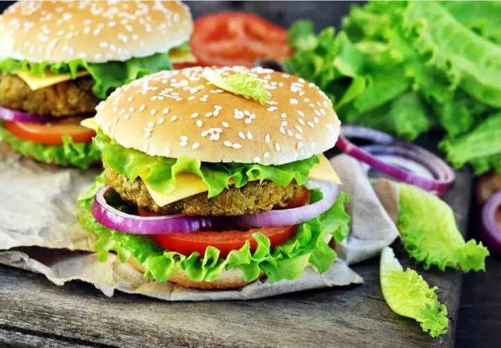 Hamburger vegetali ricetta: due succulenti hamburger con panino ai semi di sesamo, insalata croccante, pomodoro, cipolla rossa e formaggio.