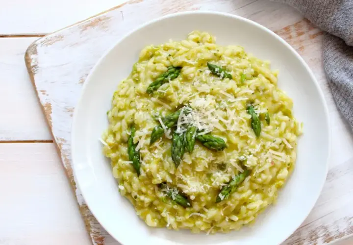 Risotto cremoso con asparagi freschi e robiola, guarnito con parmigiano grattugiato. Un piatto primaverile delizioso.