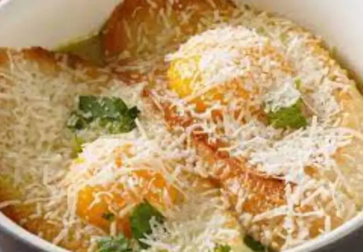 Piatto tipico Pavia: tortelli di zucca dorati, ripieni di formaggio e guarniti con erbe fresche e abbondante parmigiano grattugiato.