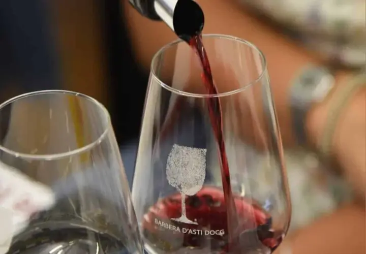 Versando il vino rosso in un bicchiere con inciso "Barbera d'Asti DOCG". Un'esperienza per gustare la barbera migliore.