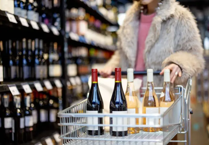 Carrello pieno di bottiglie di vino, tra cui un rosso intenso e rosati, pronto per essere portato a casa. Perfetto per una cena con amici, magari accompagnato da un buon gutturnio vino.