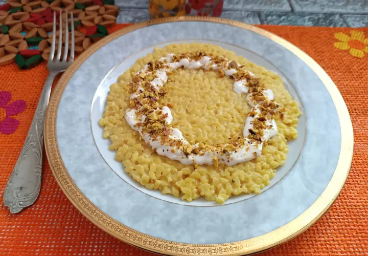 Un cremoso risotto con robiola e zafferano, guarnito con pistacchi tritati, pronto per essere gustato.