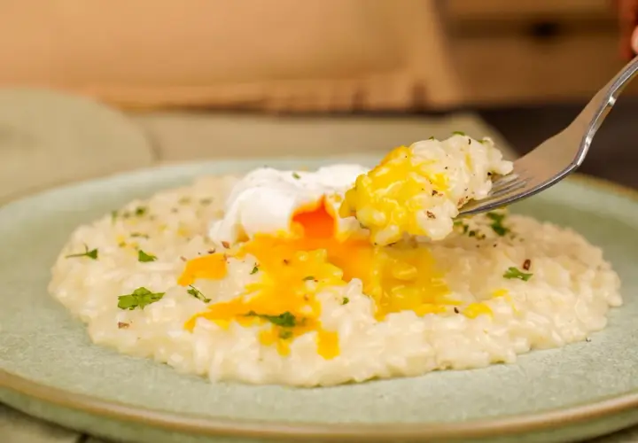 Un cremoso risotto con un uovo in camicia, il cui tuorlo dorato si riversa sul riso. Un piatto invitante e gustoso.