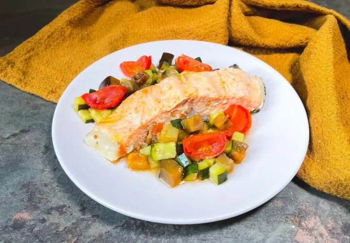Filetto di salmone su un letto di verdure miste, un'ottima idea su cosa abbinare al salmone per un pasto leggero e saporito.