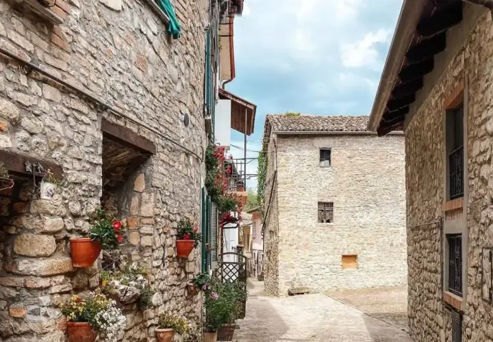 Un vicolo tra antichi borghi in provincia di Pavia, con case in pietra e vasi di fiori colorati che adornano i muri.
