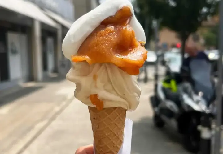 Cono con gelato artigianale, bianco e arancione, con un tocco di gelato contadino. Perfetto per una passeggiata estiva.