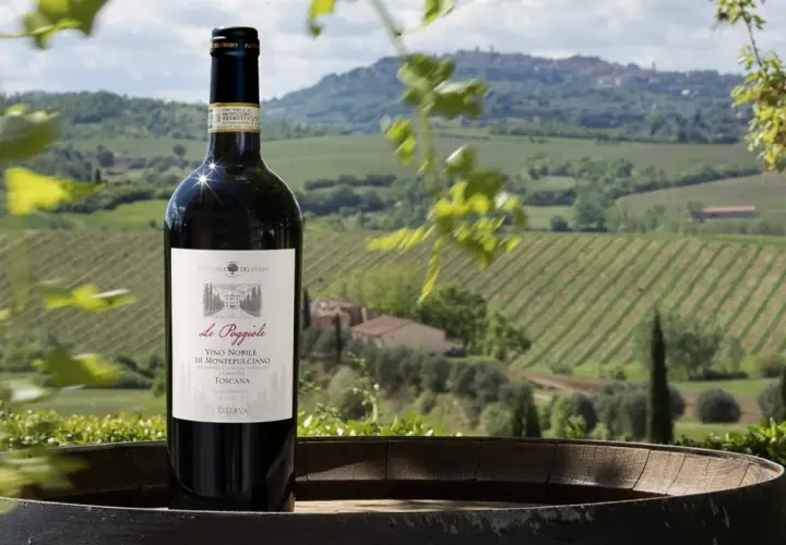 Bottiglia di Vino Nobile di Montepulciano in primo piano, con vigneti e colline toscane sullo sfondo.