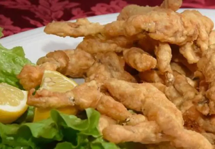 Un piatto di croccanti rane fritte, servite con spicchi di limone e foglie di lattuga fresca.