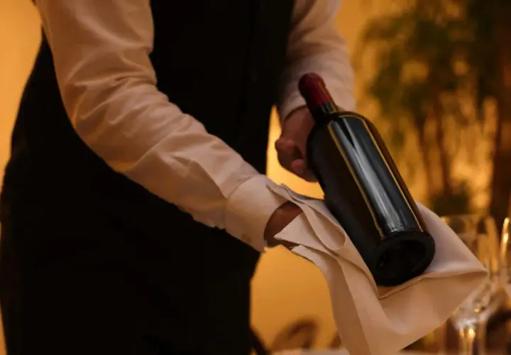 Cameriere serve un vino costoso, con eleganza, su un tovagliolo bianco.