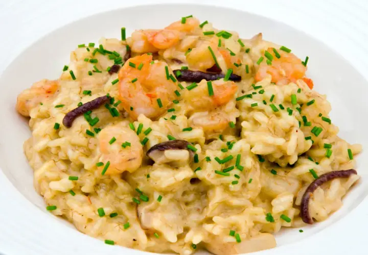 Un cremoso risotto funghi e gamberetti, guarnito con erba cipollina fresca.