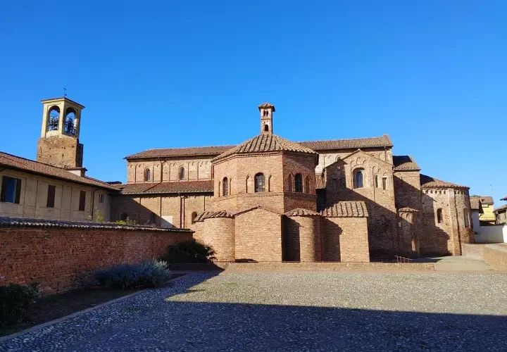 Lomello cosa vedere: la Basilica di San Magno, un gioiello romanico in mattoni rossi, con il suo campanile svettante sotto un cielo azzurro.