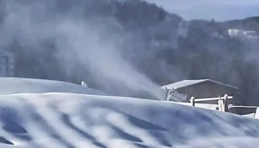 Neve artificiale sul Monte Penice, con un cannone spara-neve in azione e un rifugio sullo sfondo.