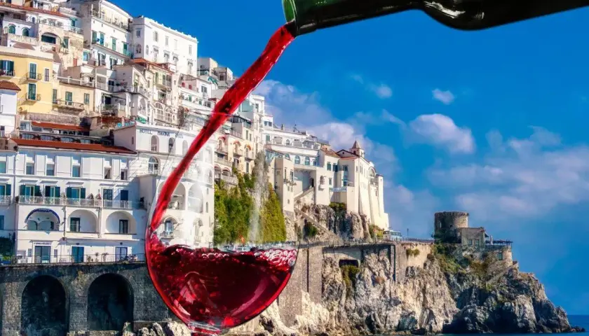 Un bicchiere di vino rosso si riempie con vista sulla costa amalfitana, un assaggio dei vini Campania.