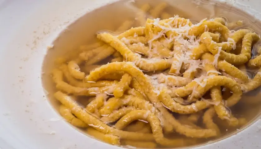 Passatelli in brodo, un classico dei cibi tipici dell'Emilia Romagna, con abbondante parmigiano grattugiato.