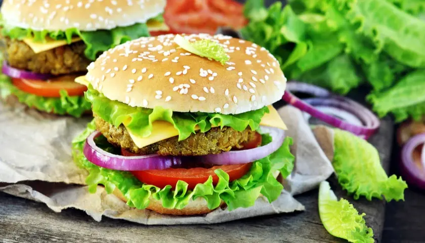 Hamburger vegetali ricetta: due succulenti hamburger con panino ai semi di sesamo, insalata croccante, pomodoro, cipolla rossa e formaggio.