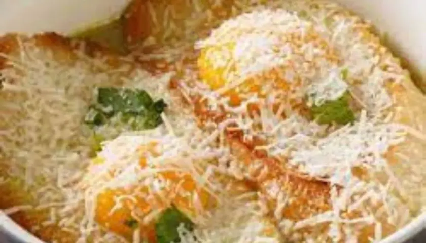 Piatto tipico Pavia: tortelli di zucca dorati, ripieni di formaggio e guarniti con erbe fresche e abbondante parmigiano grattugiato.
