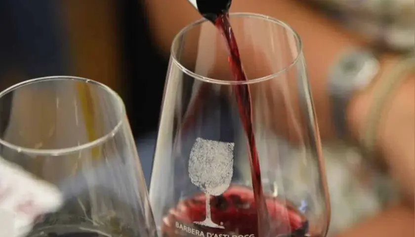 Versando il vino rosso in un bicchiere con inciso "Barbera d'Asti DOCG". Un'esperienza per gustare la barbera migliore.