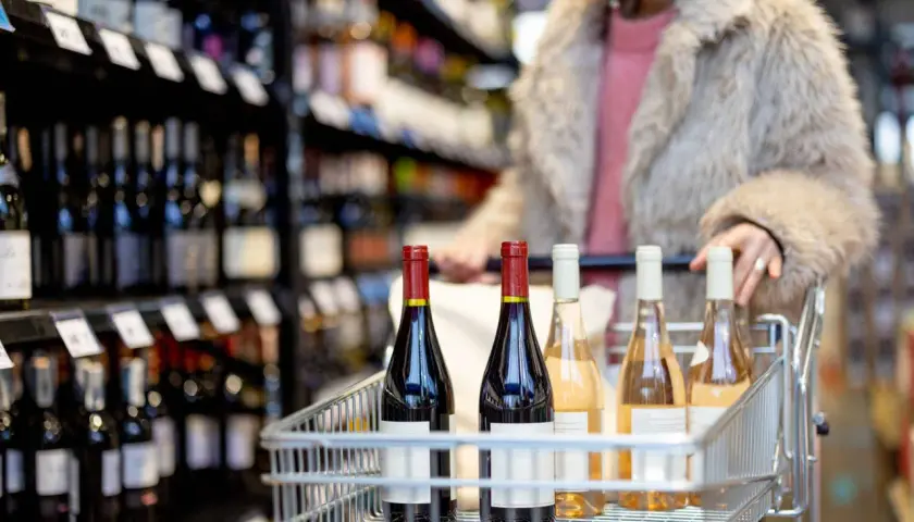 Carrello pieno di bottiglie di vino, tra cui un rosso intenso e rosati, pronto per essere portato a casa. Perfetto per una cena con amici, magari accompagnato da un buon gutturnio vino.