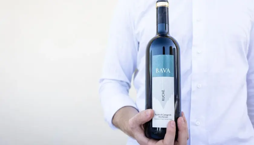 Uomo in camicia bianca tiene una bottiglia di vino Ruche di Castagnole Monferrato BAVA.